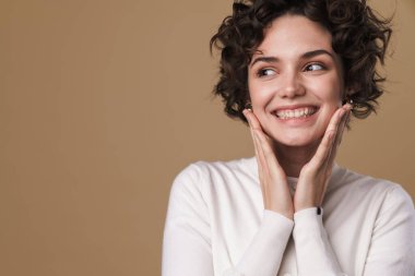 Gülümseyen ve bej arka planda izole edilmiş güzel bir kadın görüntüsü.