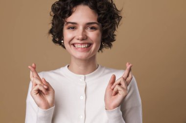 Gülümseyen güzel bir kadının el ele tutuşması bej arka planda izole edilmiş iyi şanslar.