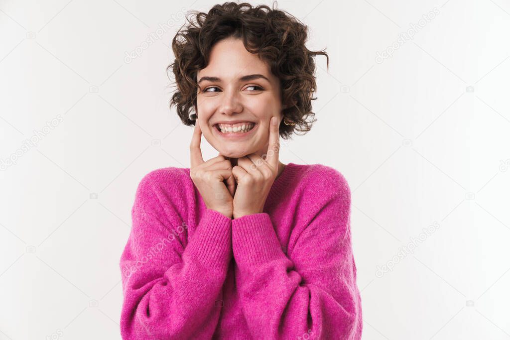 Image of happy caucasian woman smiling and pointing finger at her cheeks isolated over white background