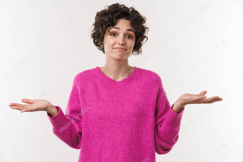 Image of young confused woman holding copyspace and looking at camera isolated over white background