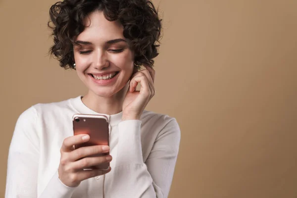 照片中快乐美丽的女人用手机 在米色背景下面带微笑 — 图库照片