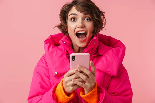 Portrait Young Surprised Woman Warm Coat Using Cellphone Screaming Isolated — Stock Photo, Image