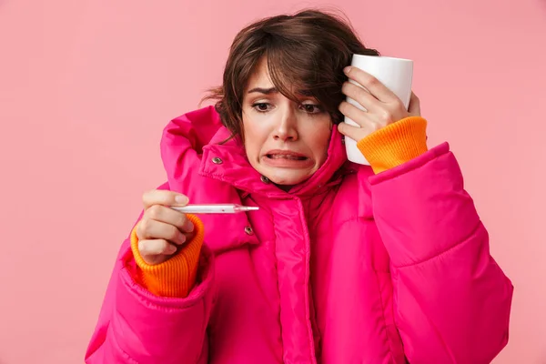 Портрет Несчастной Шокированной Женщины Теплом Пальто Чашкой Термометром Розовом Фоне — стоковое фото