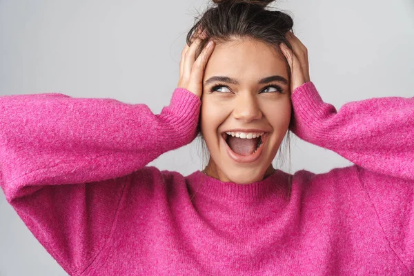 Image of nice excited woman in pink sweater smiling and grabbing her head isolated over white background