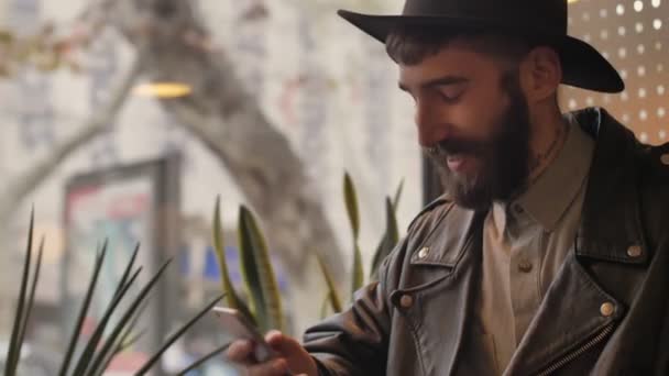 Jovem Bonito Homem Barbudo Positivo Dentro Casa Café Usando Telefone — Vídeo de Stock