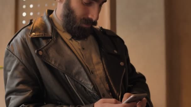 携帯電話のコーヒーを飲んでカフェで屋内でハンサムな若い髭の男 — ストック動画