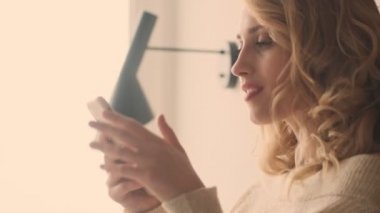 Evde cep telefonu kullanan mutlu sarışın kadın.