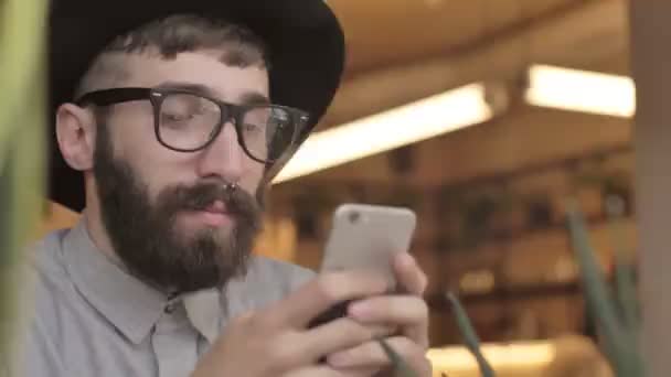 Jóképű Boldog Szakállas Férfi Egy Kávézóban Mobiltelefonnal — Stock videók