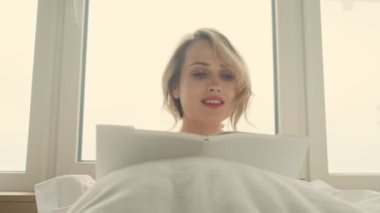 Evdeki evinde kitap okuyan mutlu, iyimser bir kadın.