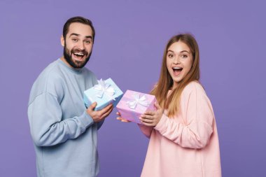 Heyecanlı, mutlu, sevgi dolu bir çiftin görüntüsü, mor arka planda izole edilmiş. Birbirlerine hediyeler veriyorlar..