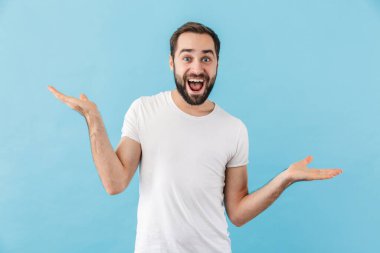 Mavi arka planda izole bir şekilde duran ve fotokopi çeken, mutlu, sakallı ve tişört giyen genç bir adamın portresi.