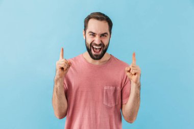 Mavi duvar arkasında izole bir şekilde poz veren genç ve yakışıklı bir adam resmi..