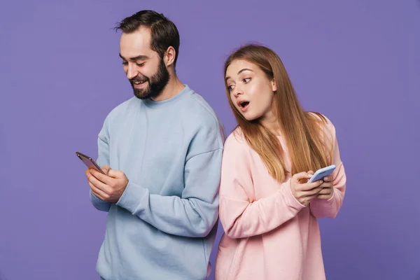混乱した女の子の写真見ます彼女の男チャットによって携帯電話隔離された上に紫の背景 — ストック写真