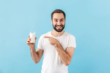 Mavi duvarın arkasında izole edilmiş, elinde süt tutan genç, pozitif adamın görüntüsü.