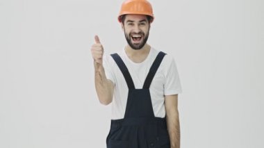 Mutlu, sakallı, genç bir adam miğferiyle beyaz duvar arkasına izole edilmiş..