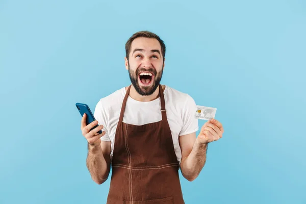 Vrolijke Jonge Man Met Baard Draagt Schort Geïsoleerd Blauwe Achtergrond — Stockfoto