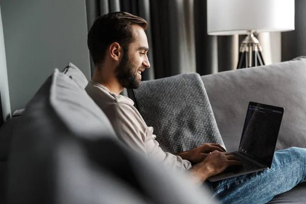 Imagen Guapo Feliz Joven Positivo Interior Casa Sofá Utilizando Ordenador — Foto de Stock