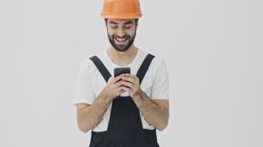 Mutlu, genç sakallı adam miğferinde cep telefonu kullanarak beyaz duvar arkasında izole edildi.