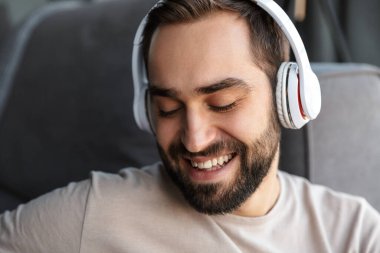 Evde kulaklıkla müzik dinleyen mutlu bir gencin görüntüsü..