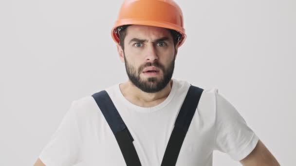怒气冲冲 满脸胡须的年轻建筑工人在白墙背景上被隔离在头盔尖叫声中 — 图库视频影像