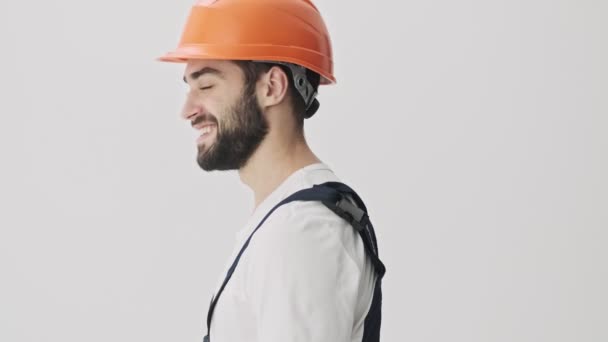 一个乐观乐观的 年轻的 留着胡子的 戴着头盔 被隔离在白墙背景之外的人做了个手势 — 图库视频影像