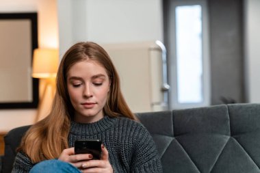 Evde cep telefonu kullanan güzel bir genç kadın resmi.