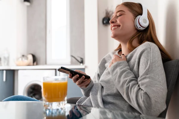 照片中的一位快乐快乐快乐的年轻女士在家里用手机听音乐 — 图库照片