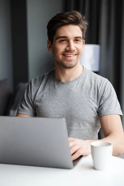 Bonito Sorridente Jovem Barbudo Vestindo Roupas Casuais Usando Computador Portátil — Fotografia de Stock