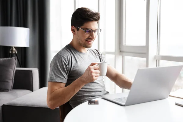 Guapo Sonriente Joven Barbudo Con Ropa Casual Usando Computadora Portátil — Foto de Stock