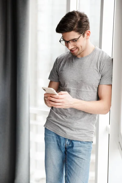 Sonriente Joven Atractivo Hombre Usando Ropa Casual Usando Teléfono Móvil — Foto de Stock