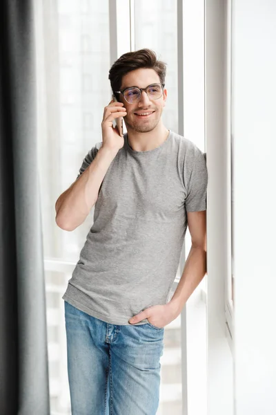 Изображение Счастливого Оптимистичного Молодого Человека Дома Разговаривающего Мобильному Телефону — стоковое фото