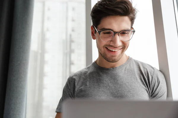 Sonriente Joven Atractivo Hombre Usando Ropa Casual Usando Computadora Portátil — Foto de Stock