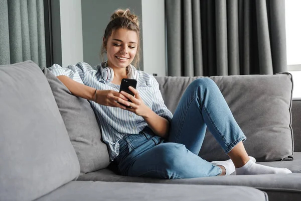 Imagem Sorrindo Mulher Agradável Com Fones Ouvido Usando Celular Enquanto — Fotografia de Stock