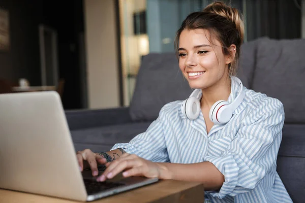 Imagem Sorrindo Mulher Agradável Com Fones Ouvido Usando Laptop Enquanto — Fotografia de Stock