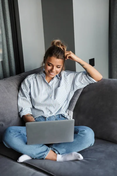 Imagem Mulher Agradável Alegre Sorrindo Usando Laptop Enquanto Sentado Sofá — Fotografia de Stock