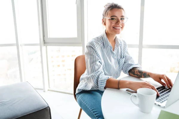 Usmívající Mladá Podnikatelka Pracující Notebooku Zatímco Sedí Kuchyni Pije Kávu — Stock fotografie