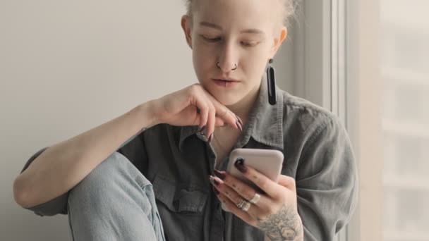 Koncentrerad Tjej Med Dreadlocks Inomhus Sitter Nära Fönstret Med Mobiltelefon — Stockvideo