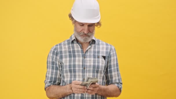 Senior Hombre Concentrado Constructor Casco Aislado Sobre Fondo Amarillo Celebración — Vídeos de Stock