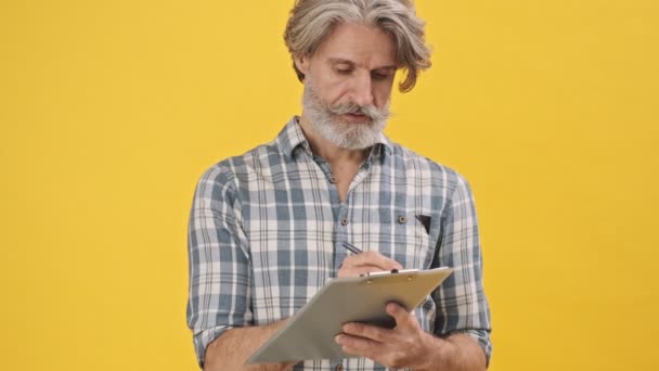 Hombre Alegre Positivo Senior Aislado Sobre Fondo Amarillo Sosteniendo Notas — Vídeos de Stock