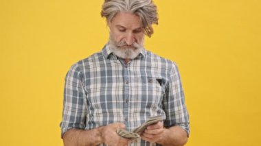 Üst düzey duygusal adam sarı arka planda izole edilmiş cep telefonuyla oyun oynuyor