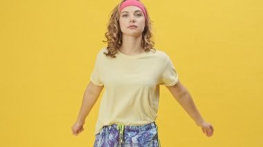 Spor kıyafetleri içinde genç ve çekici bir çift spor kıyafetleri içinde film çekiyor ve stüdyoda izole edilmiş sarı bir arka planda birlikte eğleniyorlar.