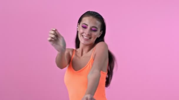 年轻而快乐的女人被隔离在粉红墙的背景下跳舞 — 图库视频影像