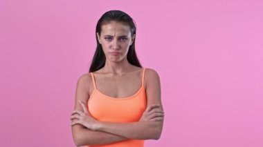Kırgın genç bir kadın pembe duvar arkasında izole edilmiş.