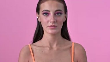 Pembe duvarın üzerinden izole edilmiş, göz kırparak göz kırpan güzel bir kadın.