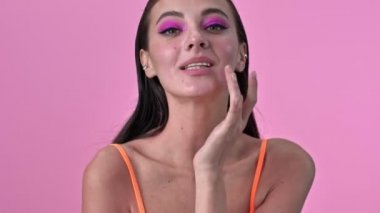 Genç, mutlu bir kadın pembe duvarın arkasında saklanıyor.