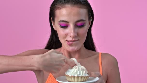 若いです正のゴージャス女性絶縁上ピンク壁背景保持カップケーキ — ストック動画