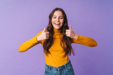 Uzun kahverengi saçlı, gülümseyen ve işaret eden başparmakları menekşe arka planda kalmış güzel bir kadın resmi.