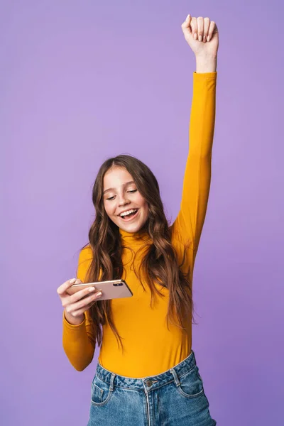 一个年轻美丽的女人 有着长长的棕色头发 带着手机在紫罗兰的背景下快乐的形象 — 图库照片