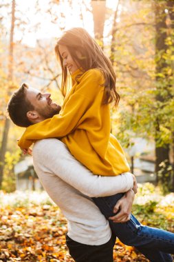 Güz parkında vakit geçirirken birbirine sarılan genç ve güzel bir çift.