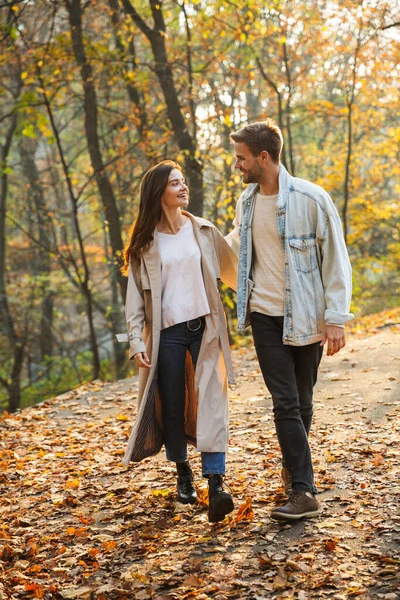 一对年轻貌美的恋人手牵着手漫步在秋天的公园里 — 图库照片